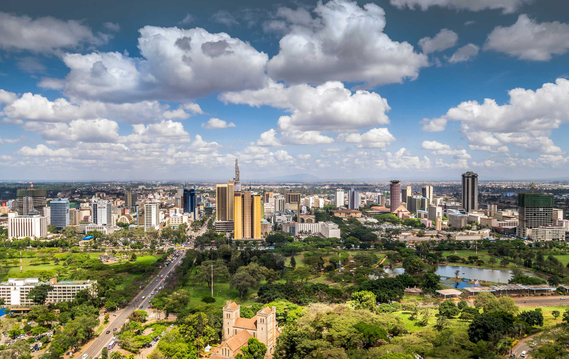Nairobi skyline overlooking green parks beneath a cloud-filled blue sky